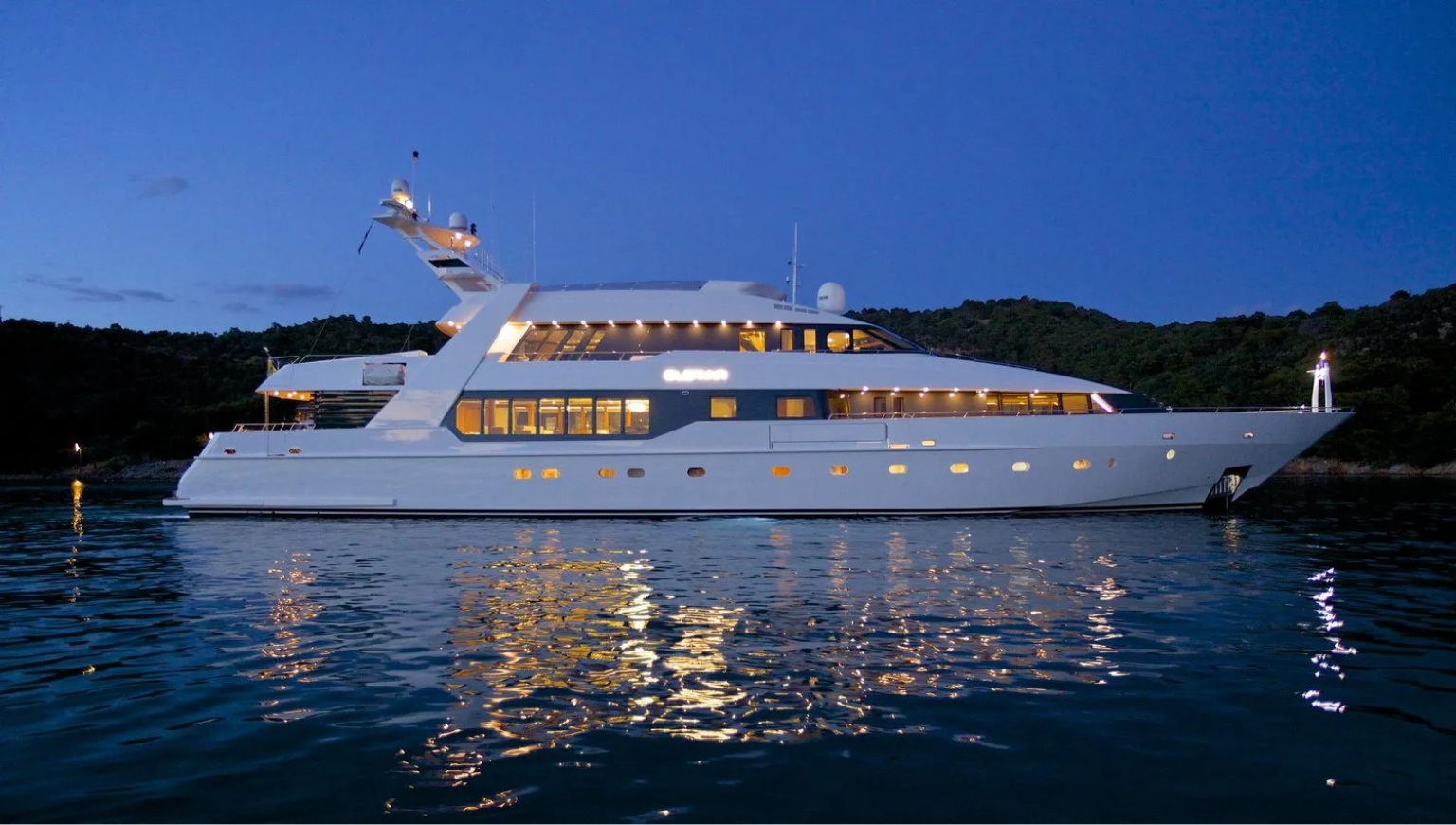 Luxury motor yacht illuminated at anchor after sunset